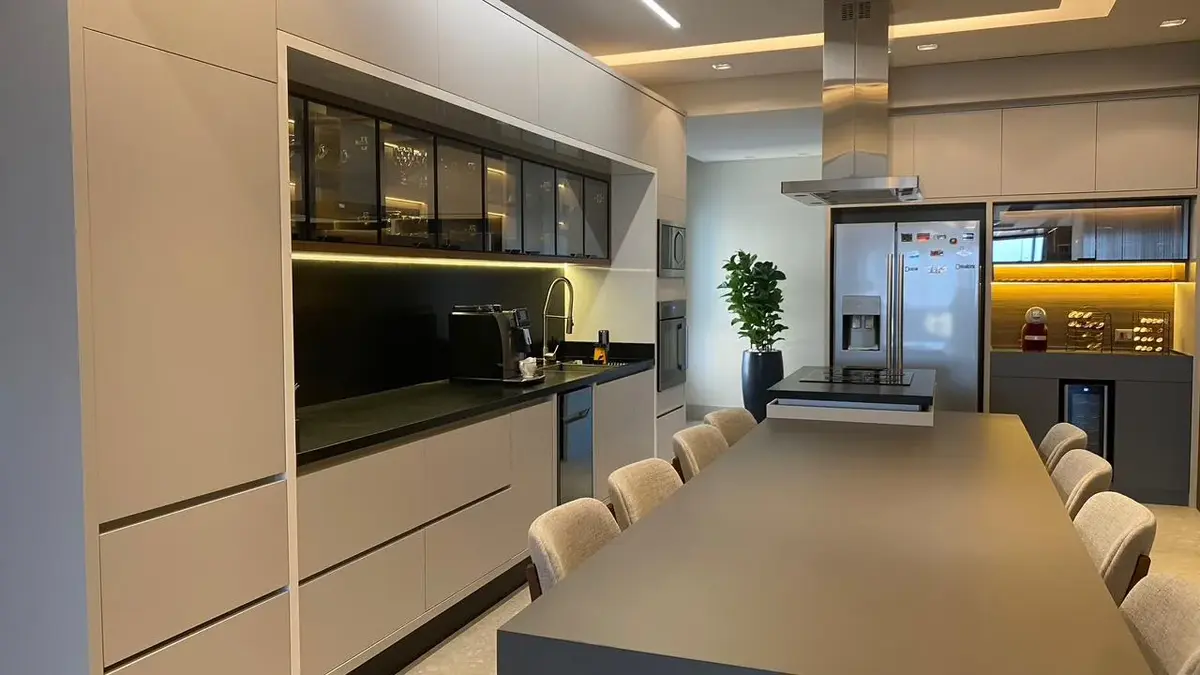 Cozinha planejada com armários do piso ao teto e cristaleira iluminada