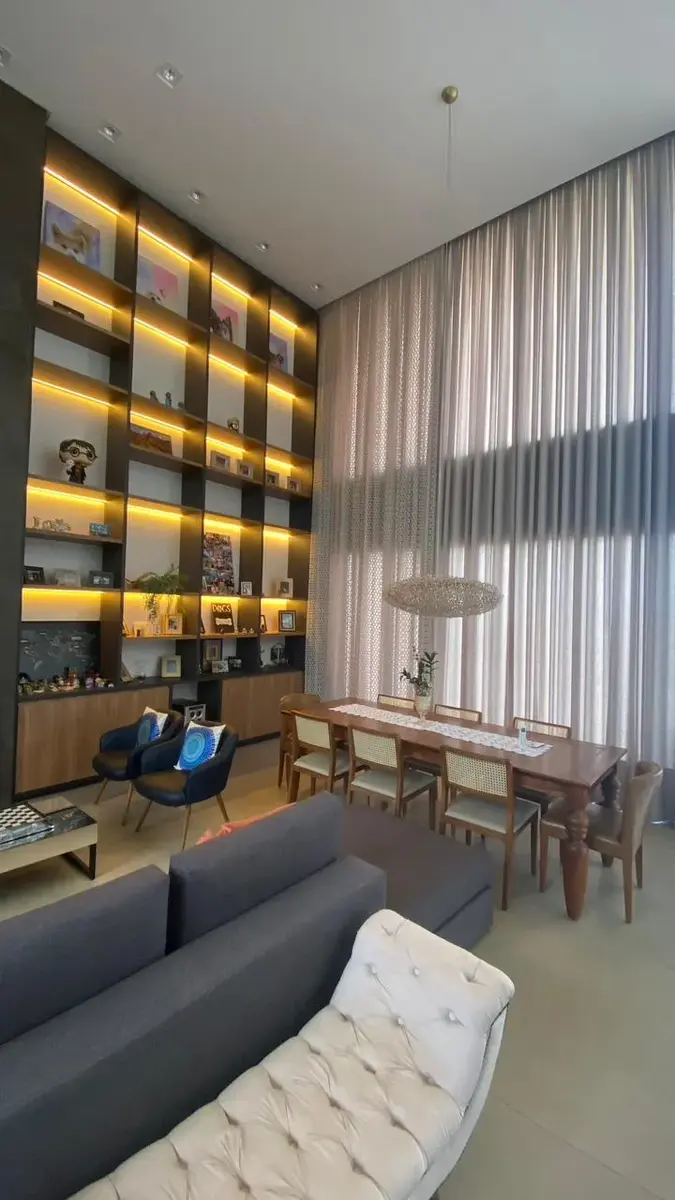 Sala com estante planejada do piso ao teto e iluminação nos nichos
